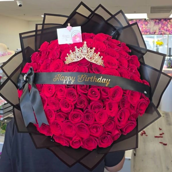 Large bouquet of red roses with a black ribbon and birthday sign
