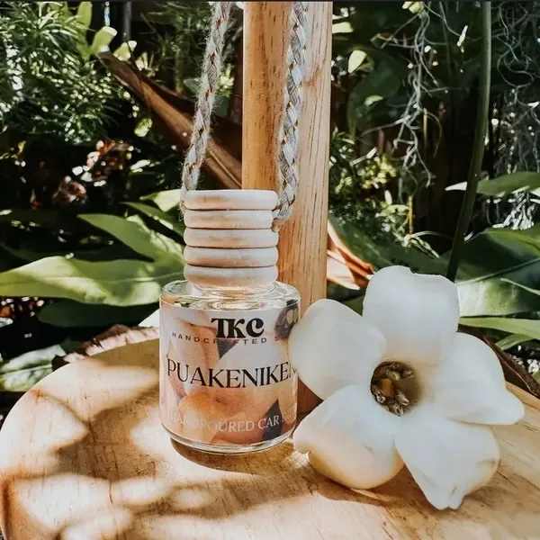 White flower-shaped candle beside a hanging glass bottle candle
