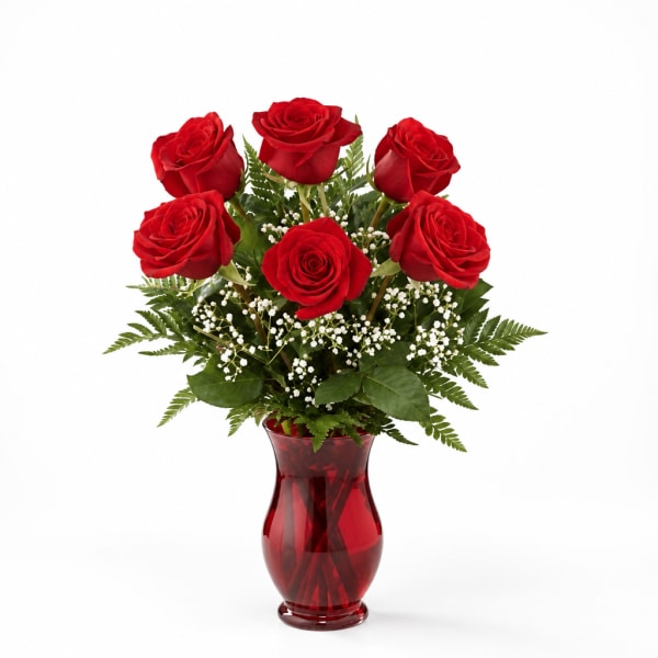 Red roses arranged in a red glass vase with white filler flowers