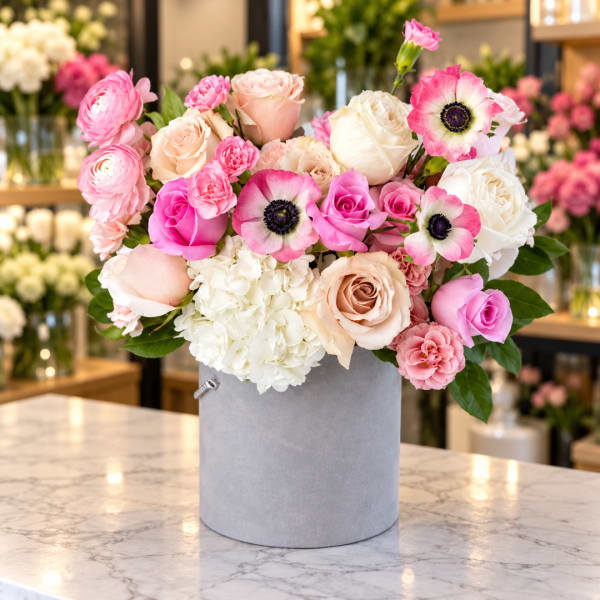 Pink and white roses with anemones in a gray hatbox
