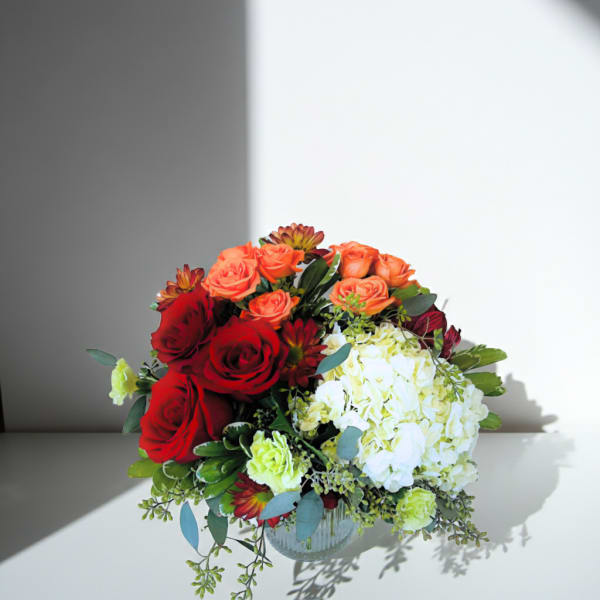 Bouquet of red and orange roses with white hydrangea in a glass vase