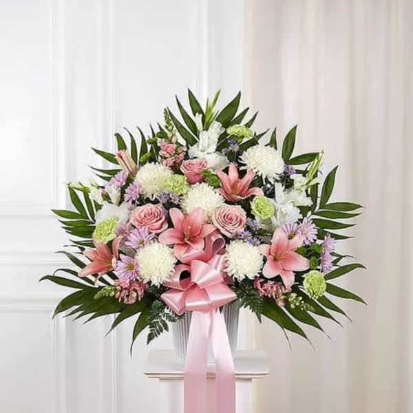 Pink and white floral spray with a ribbon bow on a stand
