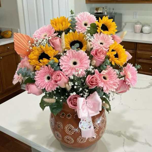 Pink gerberas and roses with sunflowers in a decorated vase