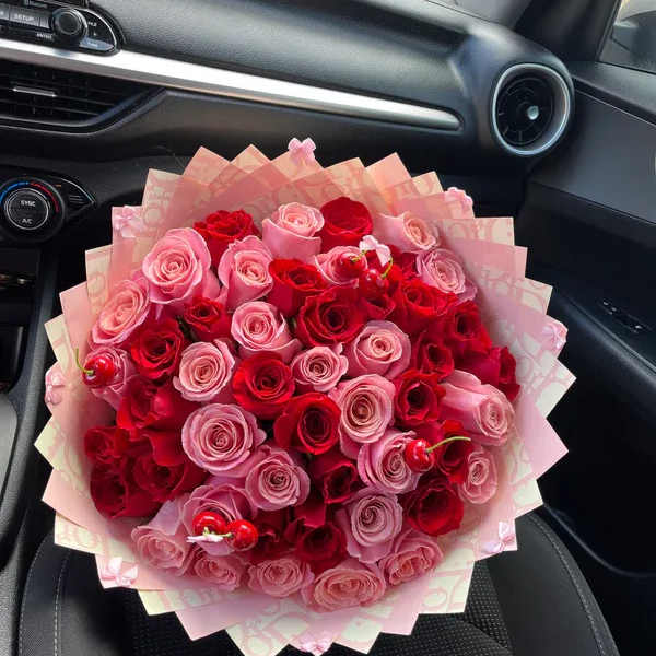 Bouquet of pink and red roses wrapped in pale pink paper