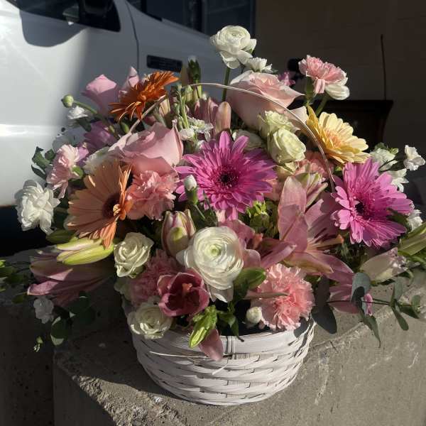 Mixed pink and white flower arrangement in a white basket
