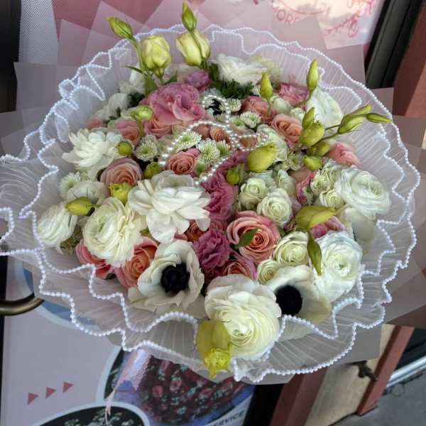 Bouquet of pink and white flowers wrapped in white lace paper