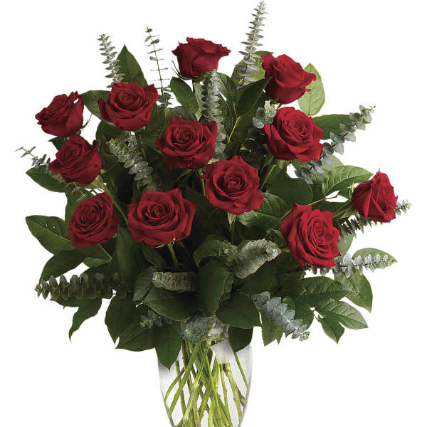 Red roses arranged in a clear glass vase with eucalyptus