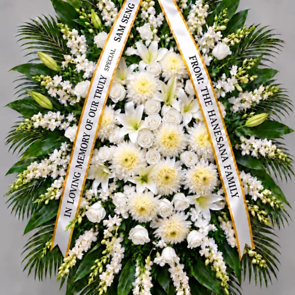 White funeral wreath with ribbon tribute and mixed blooms