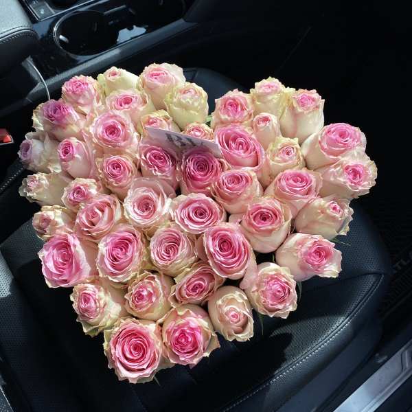 Large bouquet of pink and cream roses on a car seat