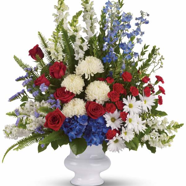 Large red, white, and blue floral arrangement in a white vase