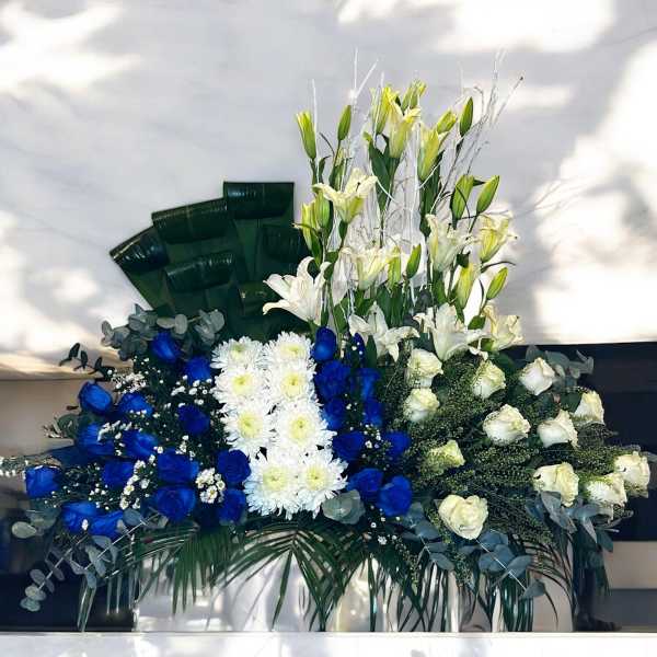 Large floral arrangement with white lilies, blue roses, and white chrysanthemums