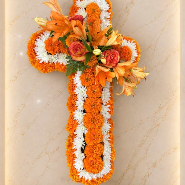 Cross-shaped floral arrangement with orange lilies, roses, and white daisies