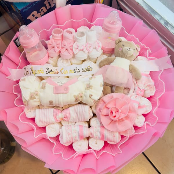 Pink baby gift bouquet with socks, bottles, and a teddy bear