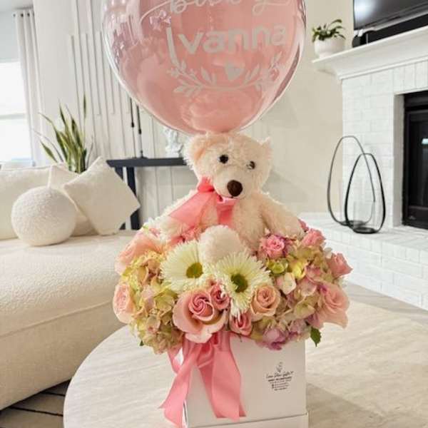 Pink baby balloon with a teddy bear and pastel flower arrangement in a box