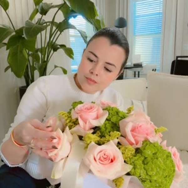 Woman holding a bouquet of pink roses and green hydrangeas in a white box