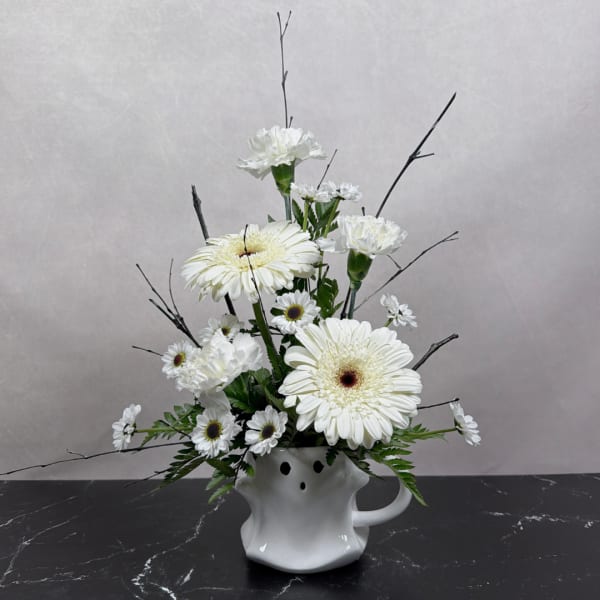 White gerbera daisies and carnations arranged in a white ceramic vase