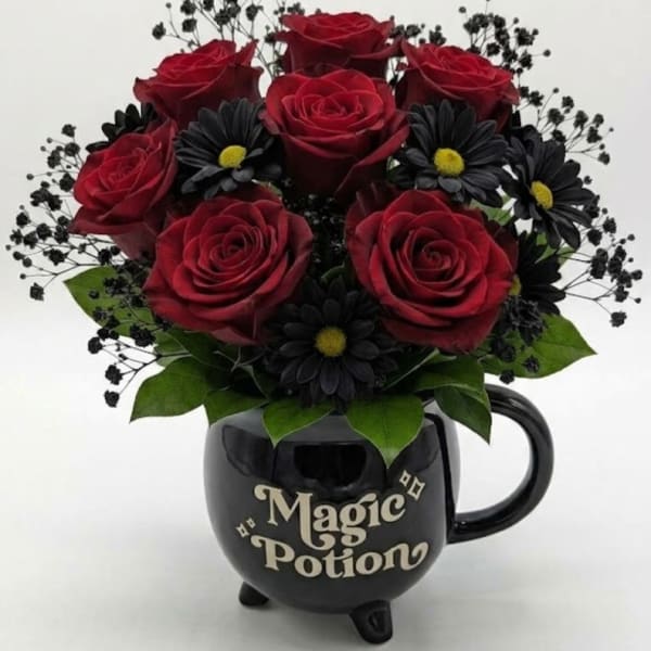 Red roses and black daisies in a black mug-shaped vase