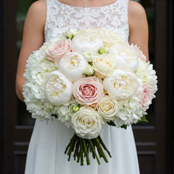 Bride holding a white and blush bouquet of roses and peonies