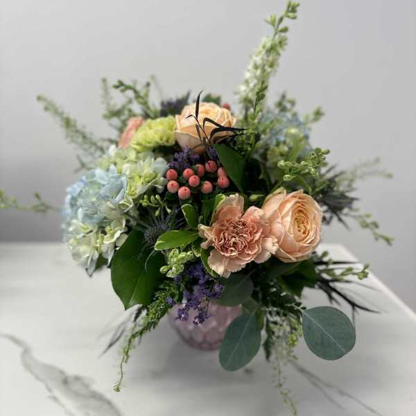 Mixed bouquet of peach and pale blue flowers in a vase
