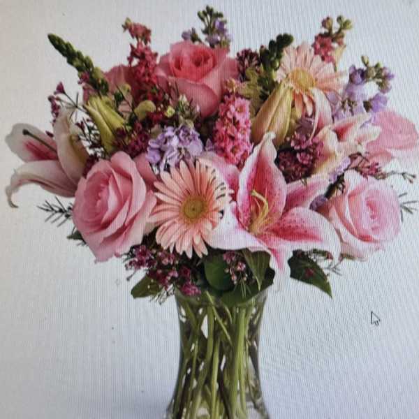 Pink roses, lilies, and gerbera daisies arranged in a clear glass vase