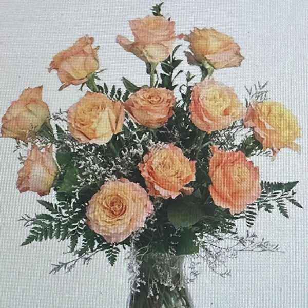 Arrangement of peach roses with white filler flowers in a clear glass vase