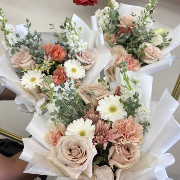 Three pastel mixed flower bouquets wrapped in white paper