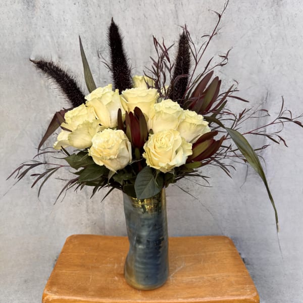 Cream rose bouquet in a tall blue glass vase