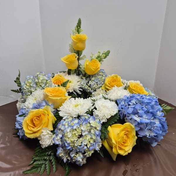 Yellow roses and blue-white hydrangeas arranged in a low floral display