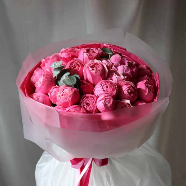 Pink rose bouquet wrapped in translucent paper with a ribbon