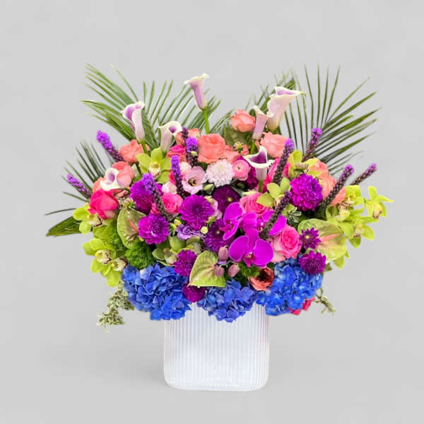 Colorful mixed bouquet in a white ribbed vase with calla lilies and orchids
