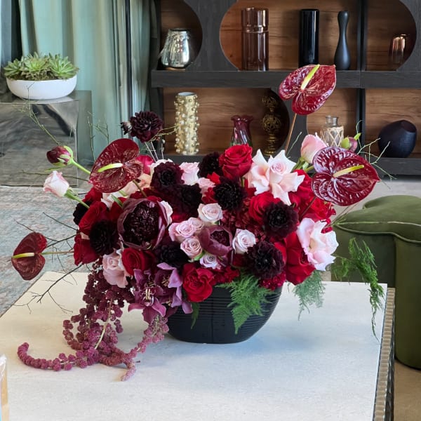 Red and pink floral arrangement in a black bowl vase