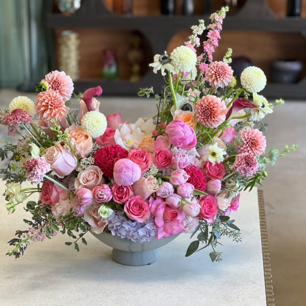Pink and white mixed flower arrangement in a low white pedestal vase