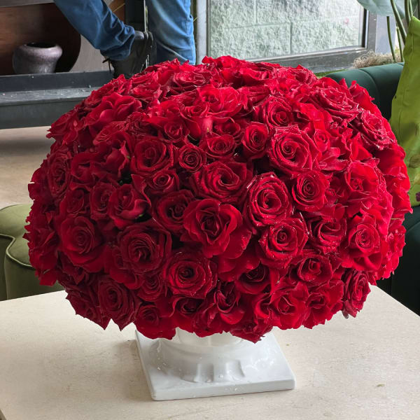 Large dome of red roses in a white pedestal vase