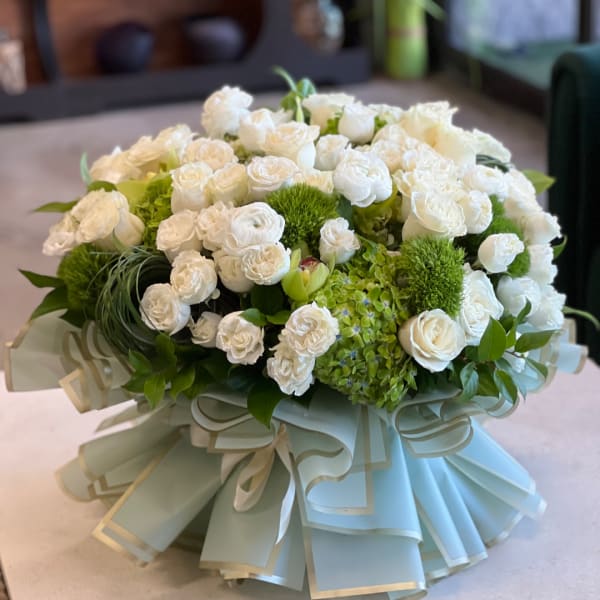 White rose bouquet with green accents and a pale blue ribbon wrap