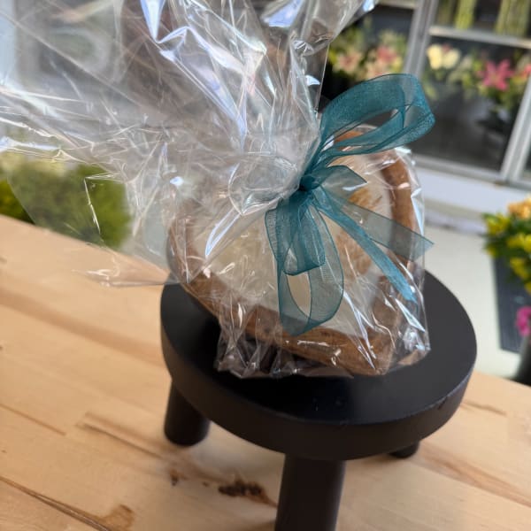 Wrapped gift basket with a teal ribbon on a small black stand