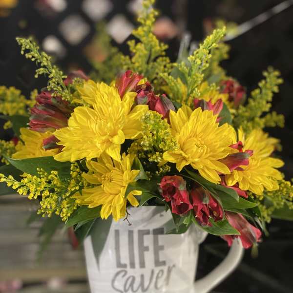Yellow and red flowers arranged in a white mug