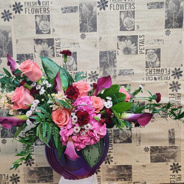 Pink and burgundy floral arrangement in a purple vase