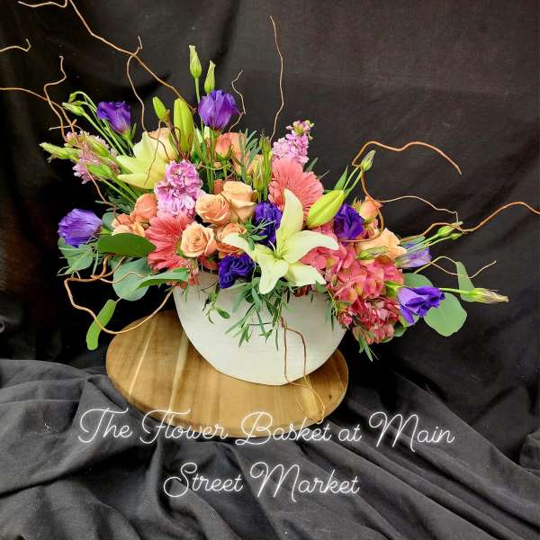 Mixed bouquet in a white bowl vase with pink, purple, and cream flowers