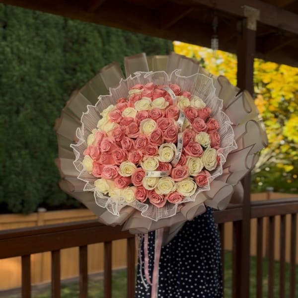 Large bouquet of pink and cream roses wrapped in beige paper