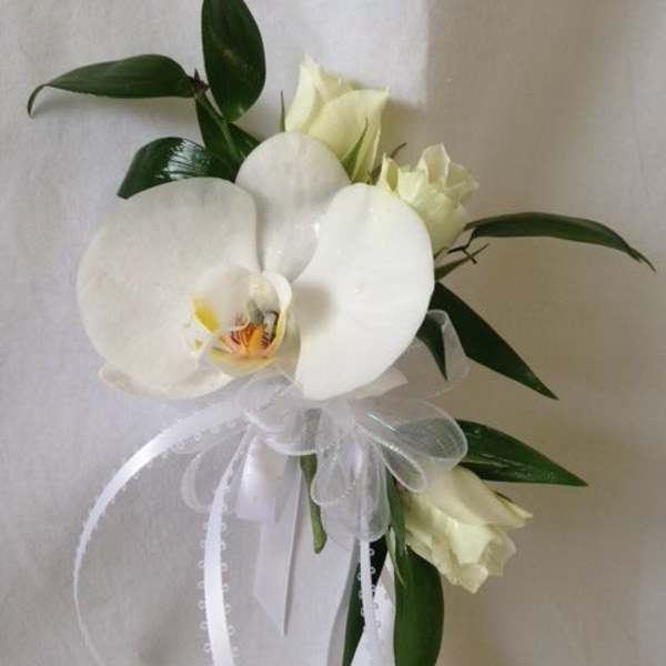 White orchid bouquet with ribbon and dark green leaves
