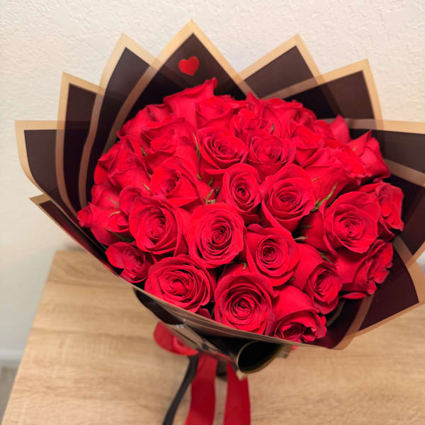 Bouquet of red roses wrapped in dark paper with a red ribbon