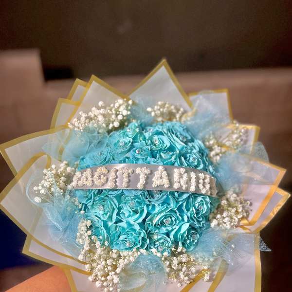 Turquoise rose bouquet with baby's breath and gold-edged wrapping
