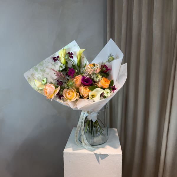 Bouquet of peach and purple flowers in a clear glass vase