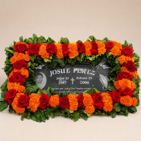 Red roses and orange marigolds arranged around a memorial plaque