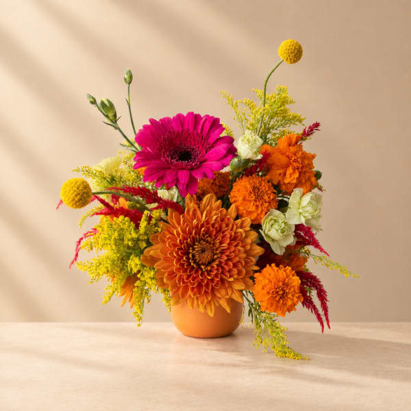 Bright mixed bouquet in an orange vase with pink, orange, yellow, and white blooms