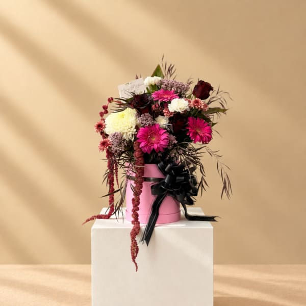 Pink and burgundy mixed bouquet in a pink hatbox with a black ribbon
