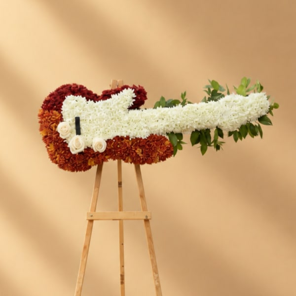 Floral guitar-shaped arrangement on a wooden easel with white and red flowers