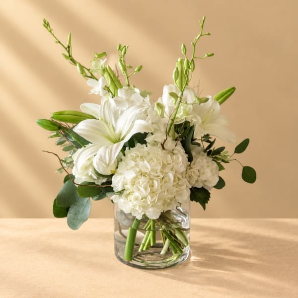 White lilies and hydrangeas in a clear glass vase