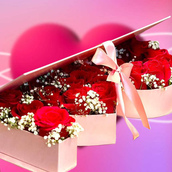 Pink heart-shaped box of red roses with baby's breath and a ribbon