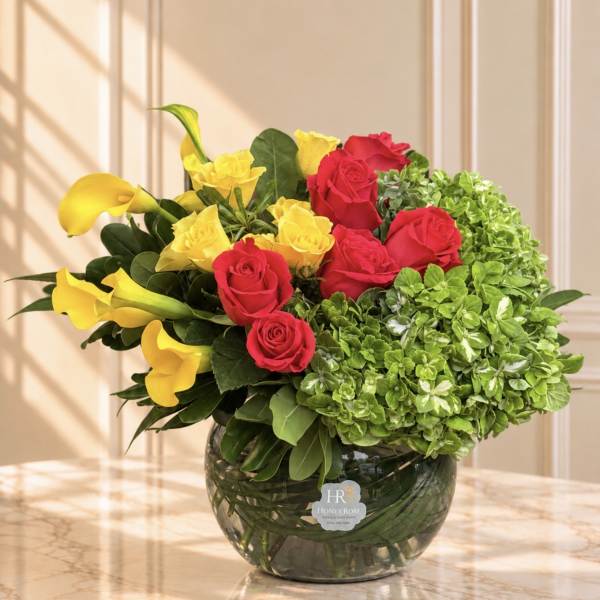 Yellow calla lilies and red and yellow roses in a glass vase